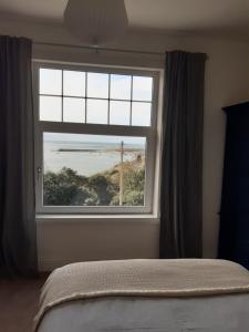 a bedroom with a window with a view of the ocean at Seasalt Loft in Barmouth