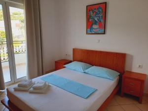 a bedroom with a bed with blue sheets and a window at Amarildo Hotel in Himare