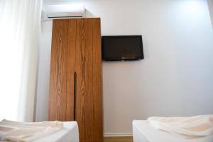 a room with two beds and a tv on a wall at Guest House Cela City Centre in Berat