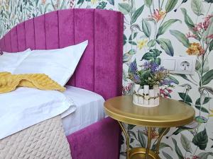 a bed with a purple headboard and a table with flowers on it at ЖК ATREA 2 room Apartment in Almaty