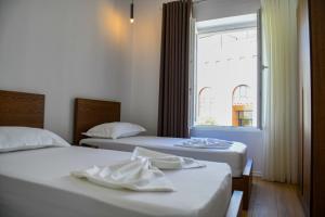 two beds in a room with a window at Guest House Cela City Centre in Berat