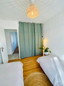 a bedroom with two beds and a green curtain at charmante maison, lumineuse. in Castelnau-dʼEstrétefonds