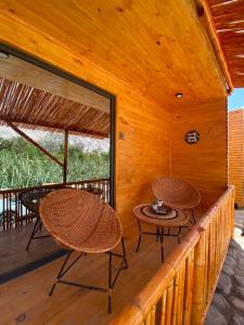 a wooden porch with two tables and chairs on it at Lodge El Pedregan in Codpa