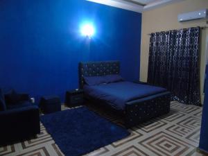 a blue room with a bed and a couch at Here is our lovely 1-Bed Apartment in Abidjan in Cocody