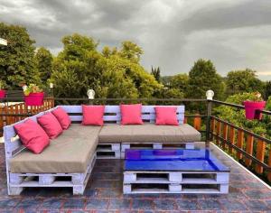 Eine Bank mit rosa und blauen Kissen auf einer Terrasse in der Unterkunft Paradiso Hotel in Telawi