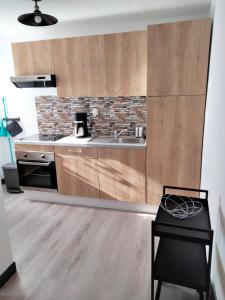 a kitchen with wooden cabinets and a sink and a stove at L'ECUME in Pléboulle