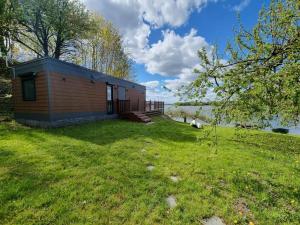 a small cabin in the grass next to a lake at GARDENIA RAJGRÓD in Rajgród