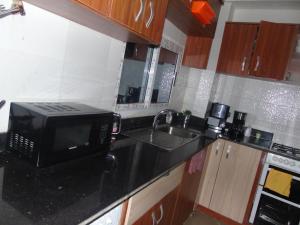 a kitchen counter with a microwave and a sink at Here is our lovely 1-Bed Apartment in Abidjan in Cocody