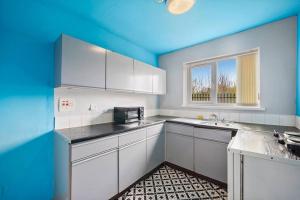 a kitchen with white cabinets and a blue ceiling at Cosy Retreat: Near Attractions & Comfortable! in Birmingham