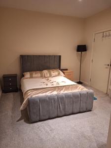a bedroom with a large bed with a gray headboard at Fabulous Home from Home - Central Long Eaton - Lovely Short-Stay Apartment - HIGH SPEED FIBRE OPTIC BROADBAND INTERNET - HIGH SPEED STREAMING POSSIBLE Suitable for working from home and students Very Spacious FREE PARKING nearby in Long Eaton