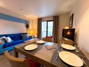 a living room with a table and a blue couch at DANS LES BRAS DE NEPTUNE - Plage de TRESTRAOU - Piscine - 4 à 5 personnes in Perros-Guirec