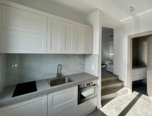 a kitchen with white cabinets and a sink at Sterna Suites in Paralía Kímis