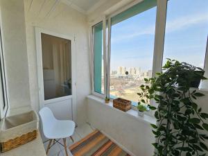 a white chair in a room with a window at ЖК ATREA 2 room Apartment in Almaty