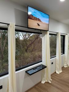 a living room with a flat screen tv and two windows at Robyn’s Nest in Scarborough