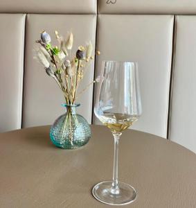 een glas wijn en een vaas met bloemen op een tafel bij SKLEP 38 in Velké Bílovice