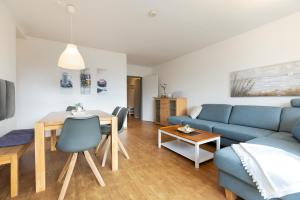 uma sala de estar com um sofá azul e uma mesa em W4 - Gästehaus Christian-Westphal-Str 60 - FERIENDOMIZIL HOLLICH em Grömitz