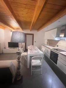 Grazioso appartamento في أَويستا: مطبخ بطاولة بيضاء وطاولة وكراسي