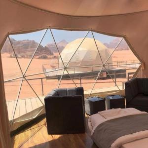 a tent with two beds and a view of the desert at desert wadi rum camp in Wadi Rum