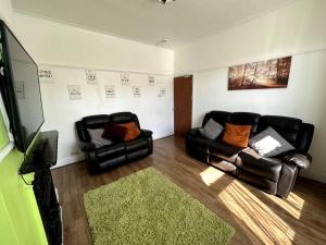 un soggiorno con 2 sedie in pelle e una TV di Spacious Holiday Home Near Tube Station - By Starlet Stays a Londra