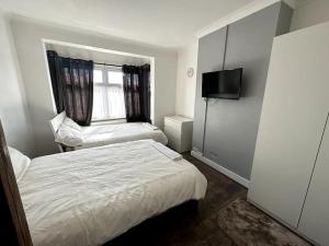 a small bedroom with two beds and a television at Spacious Holiday Home Near Tube Station - By Starlet Stays in London