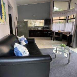 Una sala de estar con un sofá negro y una mesa. en Residencias Arenal, en Fortuna