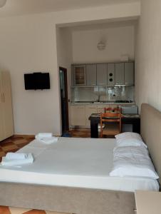 two beds in a room with a kitchen and a table at Hotel Sirena in Vlorë