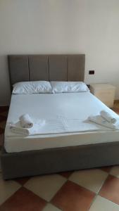 Una cama con sábanas blancas y dos toallas. en Hotel Sirena, en Vlorë