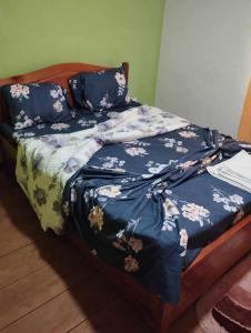 a bed with a blue comforter with flowers on it at Pousada Bem Posta in São Tomé