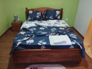 a bed with a blue comforter with flowers on it at Pousada Bem Posta in São Tomé