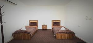 two beds in a room with two tables at Blue Bird House in Wadi Musa