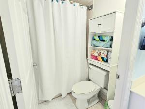 a bathroom with a white shower curtain and a toilet at Stay ON the beach! Wonderful location! in Daytona Beach