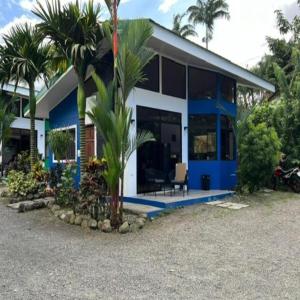 a blue and white house with a palm tree at Residencias Arenal in Fortuna