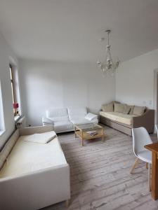 ein Wohnzimmer mit weißen Möbeln und einem Kronleuchter in der Unterkunft Ferienwohnung mit Blick auf die Elbe und den Lilienstein in Königstein an der Elbe