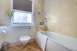 a bathroom with a toilet and a tub and a window at Stunning 4 Bedroom House in London