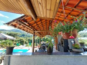 une terrasse avec un toit en bois orné de plantes et une piscine dans l'établissement Pousada Pé na Montanha, à Socorro
