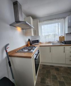 een keuken met witte kasten en een fornuis met oven bij Modish 1Bed Apartment with Free Street Parking in Scunthorpe
