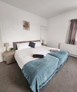 a large white bed with a blue blanket on it at Modish 1Bed Apartment with Free Street Parking in Scunthorpe