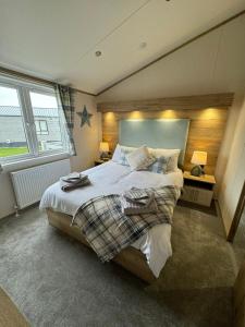 a bedroom with a large bed and two windows at Golden Anchor - The Oakland Lodge - Coastal Caravan Breaks in Chapel Saint Leonards