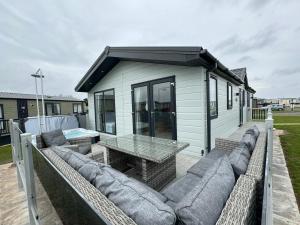 a patio with a couch and a table and a building at Golden Anchor - The Oakland Lodge - Coastal Caravan Breaks in Chapel Saint Leonards