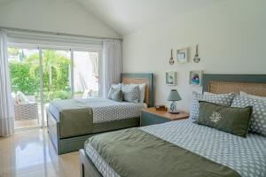 a bedroom with two beds and a sliding glass door at Xeliter Green One Playa Dorada in San Felipe de Puerto Plata