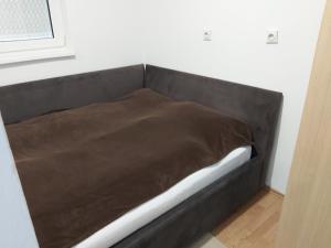 a bed with a brown blanket in a room at Apartman Zenica in Zenica