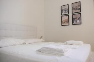 un letto bianco con lenzuola bianche e quadri sul muro di Via Gattini Suite a Matera