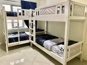 Ramble stay Hostel Bur Dubai في دبي: سريرين بيض بطابقين في غرفة