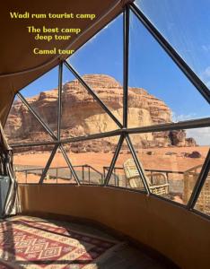 a bedroom with a view of the desert from a window at desert wadi rum camp in Wadi Rum