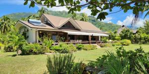 a house with a garden and mountains in the background at Villa Tiarenui in Maharepa