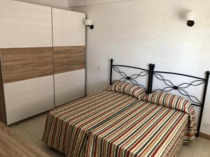 a bedroom with a bed with a striped comforter at Apartamento con vistas al mar, Punta Umbria in Punta Umbría