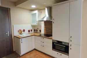 a kitchen with white cabinets and a sink at Apartamentos Villa Sofía in San Vicente de la Barquera