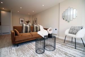 a living room with a brown couch and a white chair at Casablanca 4 - Cardiff Bay - 2 Bed Apartment in Cardiff