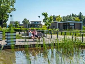 zwei Leute sitzen auf einer Bank neben einem Teich in der Unterkunft Nice apartment in Olburgen in Olburgen