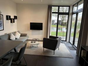 ein Wohnzimmer mit einem Sofa, Stühlen und einem TV in der Unterkunft Nice apartment in Olburgen in Olburgen